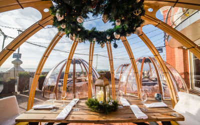 Brighton igloo at Shelter Hall on Brighton seafront. In foreground a wooden table laid for dinner with cutlery and napkins. A perfect option for Valentines Day Brighton