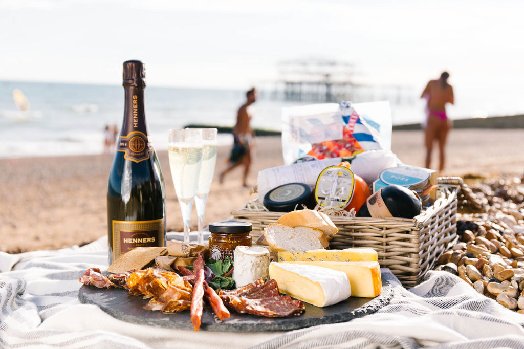 Charcuterie and cheese in a basket on Brighton beach with the West Pier in the background. Perfect for a picnic on the beach or a Brighton Valentines Day