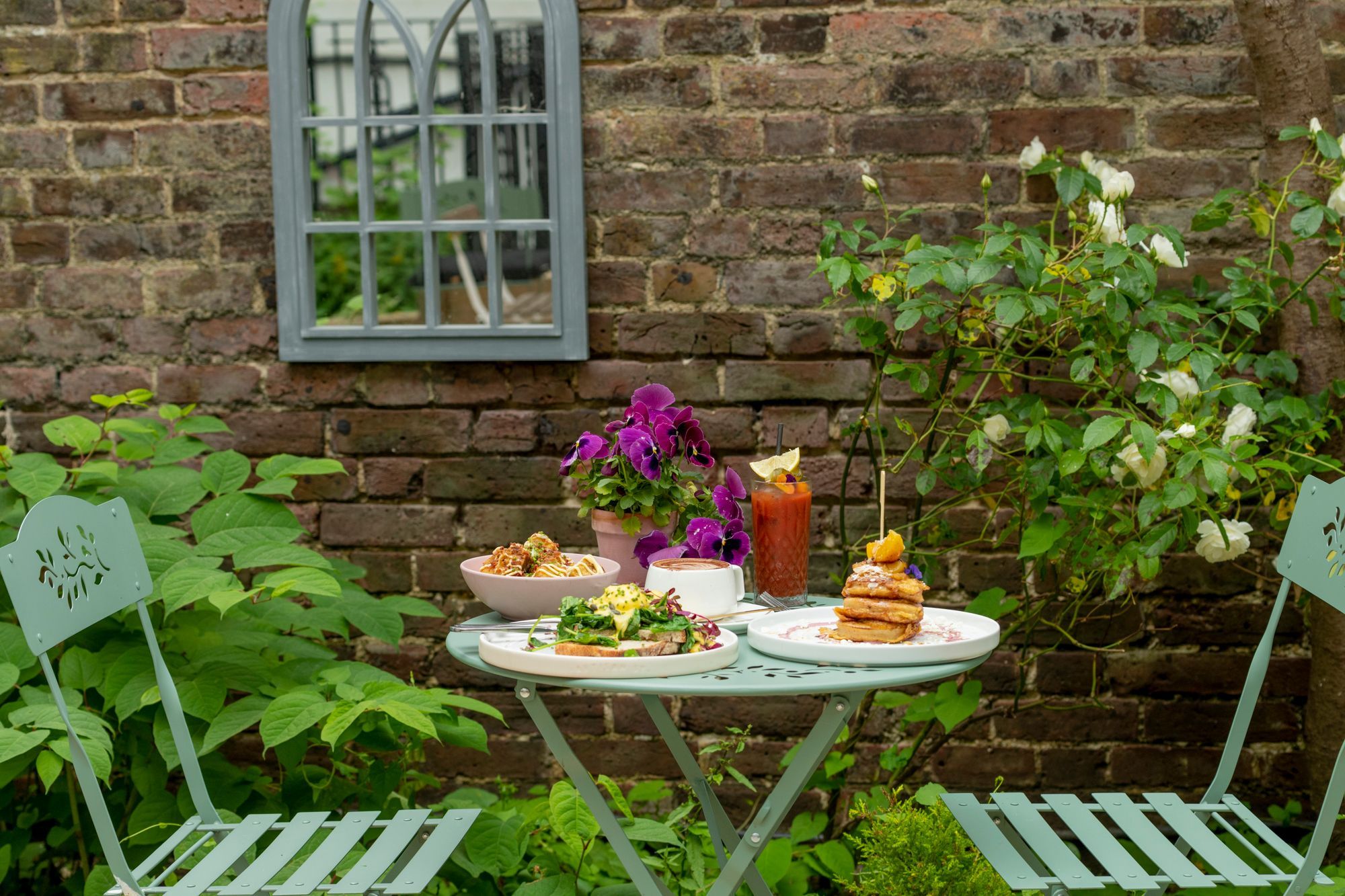 secret garden spot at the Oeuf, two light green chars and table laid out with brunch