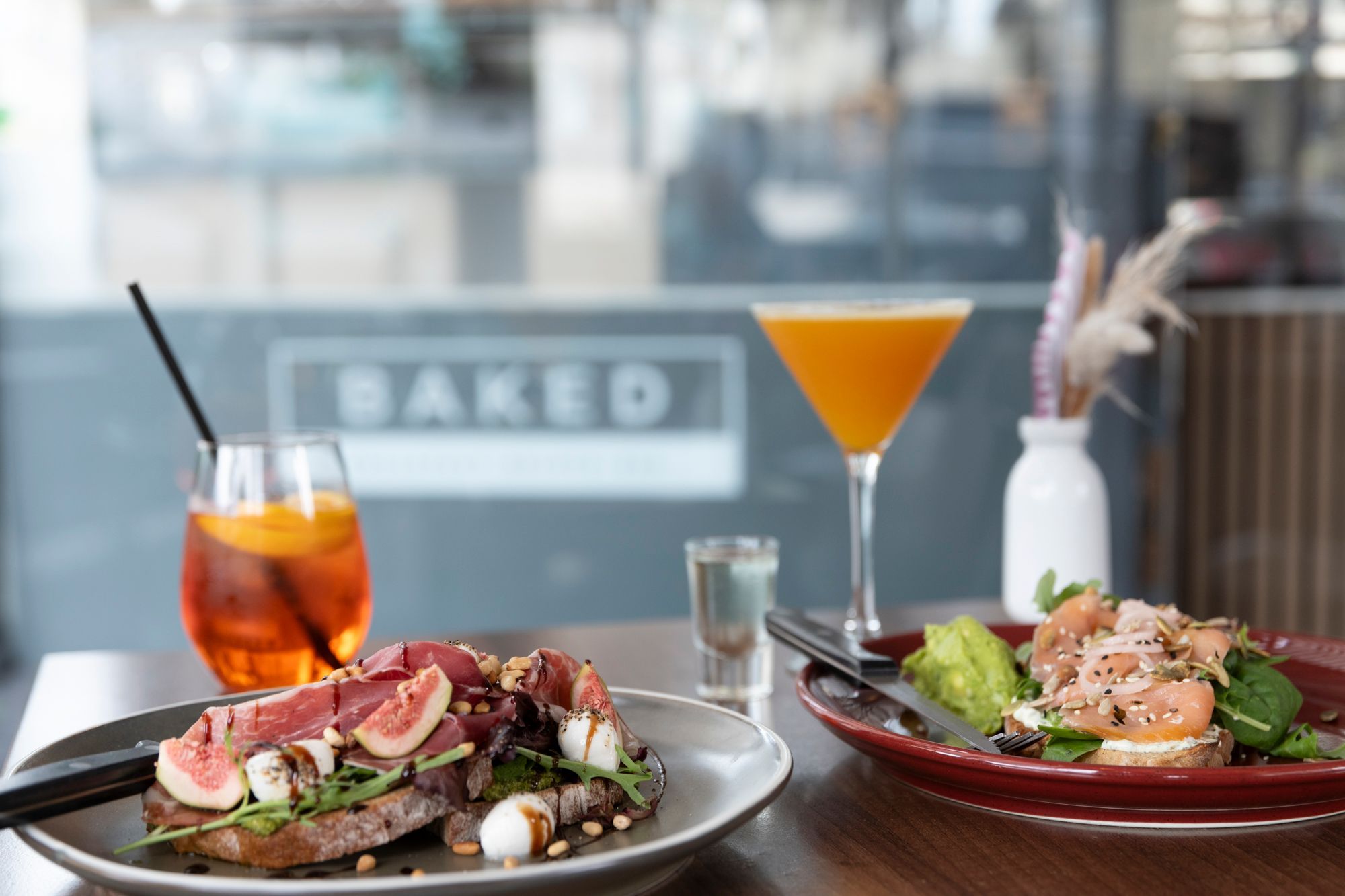 side shot of the dark brown table laid out with two brunch dishes served with two types of cocktails at baked hove