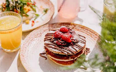 American pancakes covered in chocolate and with raspberries on the top