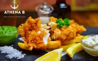 Athena B Athena B for Brighton takeaway. Pictured crispy cod aith chips and mushy peas on a black slate with a side of lemon