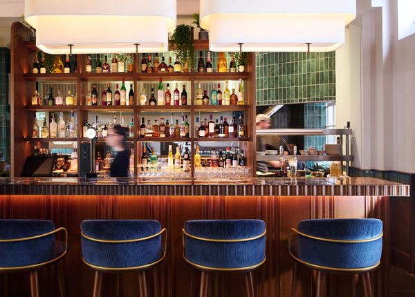 bar area of Tutto., shelves filled with different types of alcohol drinks, blue bar stools