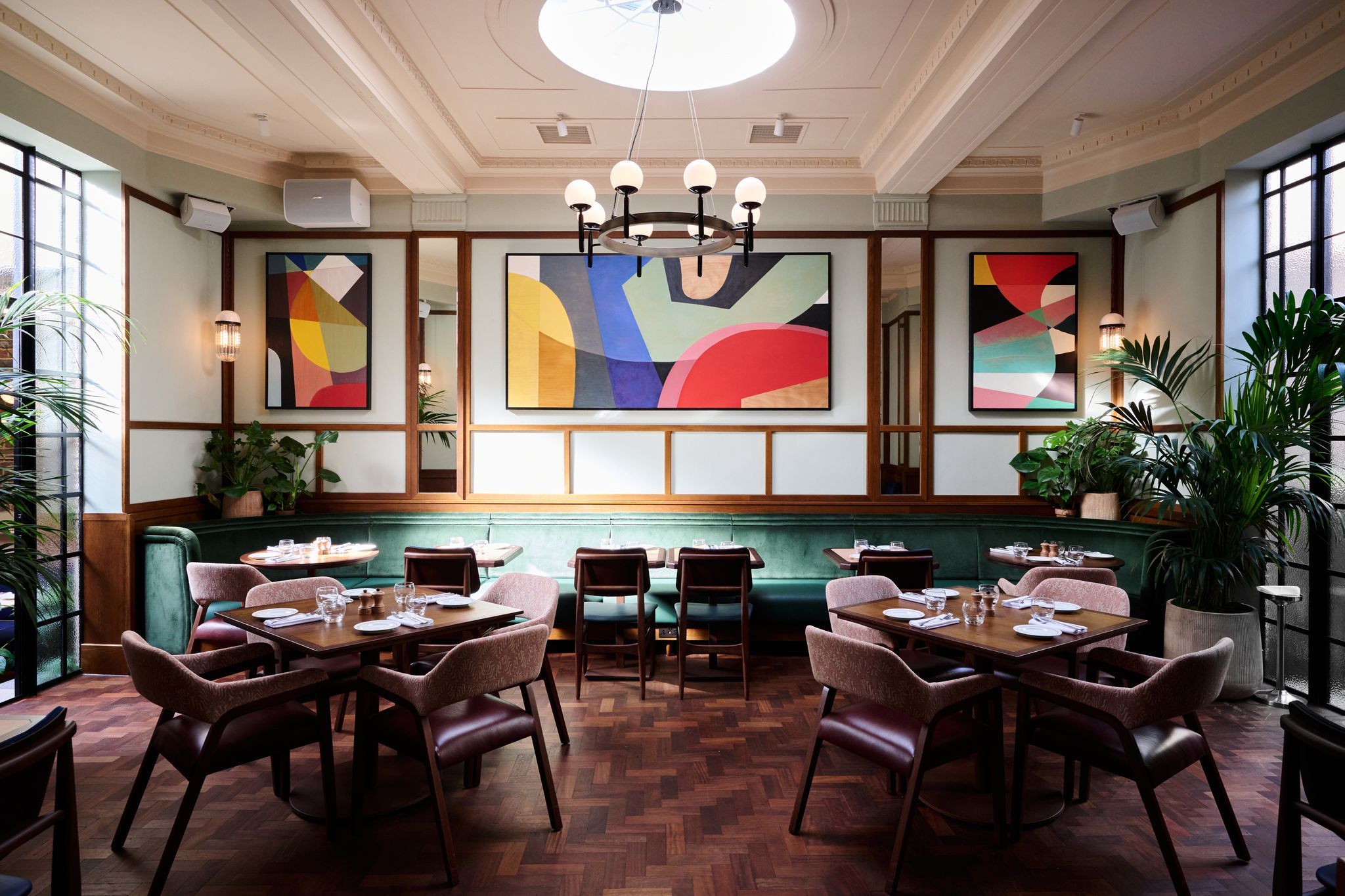 interior shot of the Tutto, light green walls with colorful paintings, brown tables and chairs