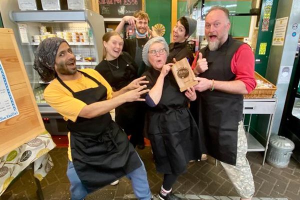 Five people in black aprons crowd around a BRAVO trophy smiling and pulling funny faces