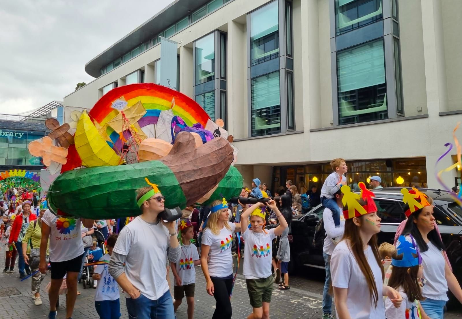happy parade next to brigton library, they are carrying rainbow boat