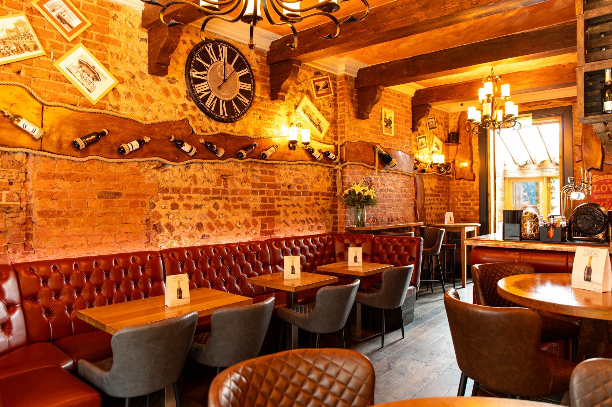 Paris Wine Bar interior shot, brick walls decorated with bottles of wine, diner seating area with chairs, dim lights
