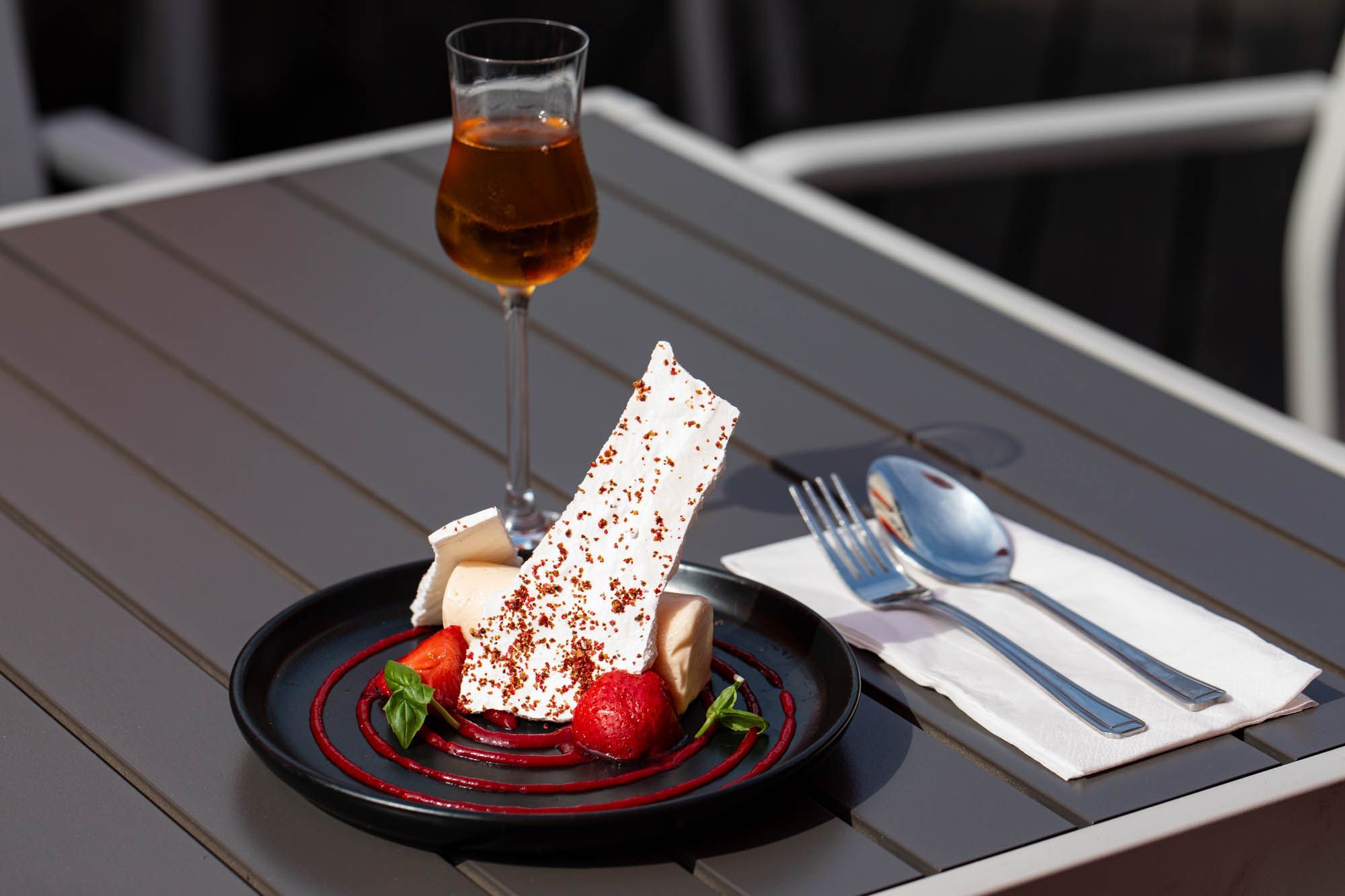 dessert served in black round plate with glass of alcohol on the garden table at the daddylonglegs