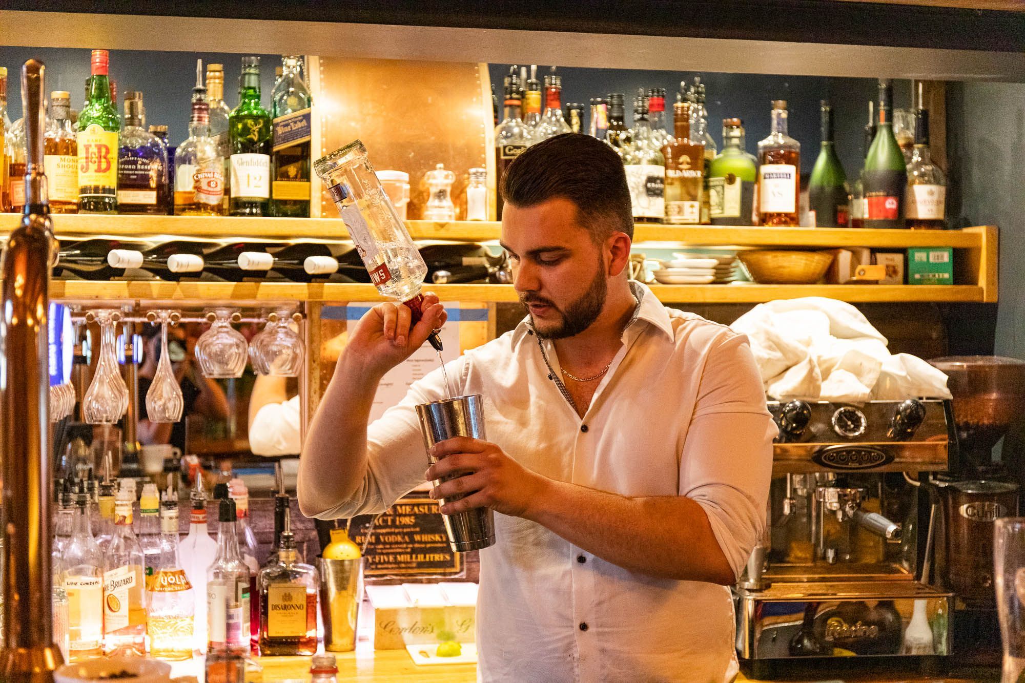 bartender sipping vodka into mixing cup - Paris Wine Bar