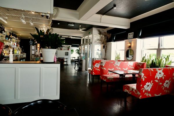interior of DaddyLonglegs food and wine pub, white bar area, read coloured diners with white flowers on