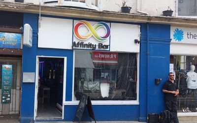 A blue fronted bar with a rainbow affinity symbol over the window and a door to the left