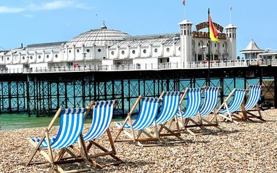 brighton beach, white and blue chars and Brighton pier in bbackground