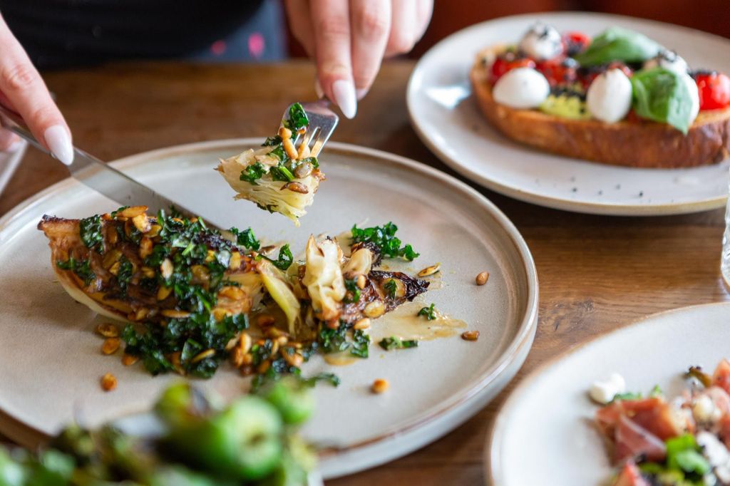 hands holding cutlery and cutting into green looking dish