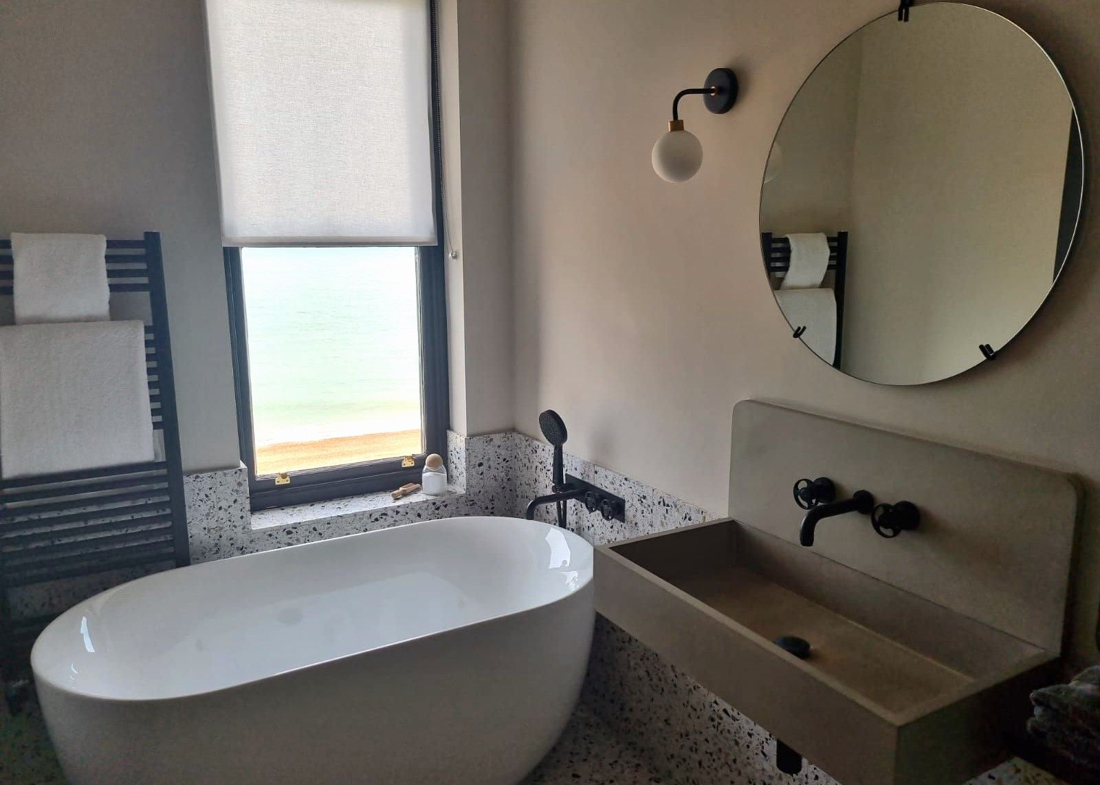 the port hotel bathroom, bath tub with window view, mirror, sink and towels