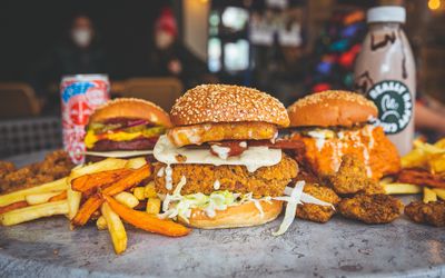 close up shot of three vegan burgers with fries and sweet potato