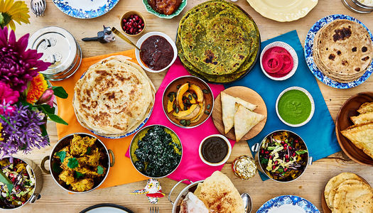 Colourful Majahma feast. Lots of dishes laid out on a wooden table to plates and sides.