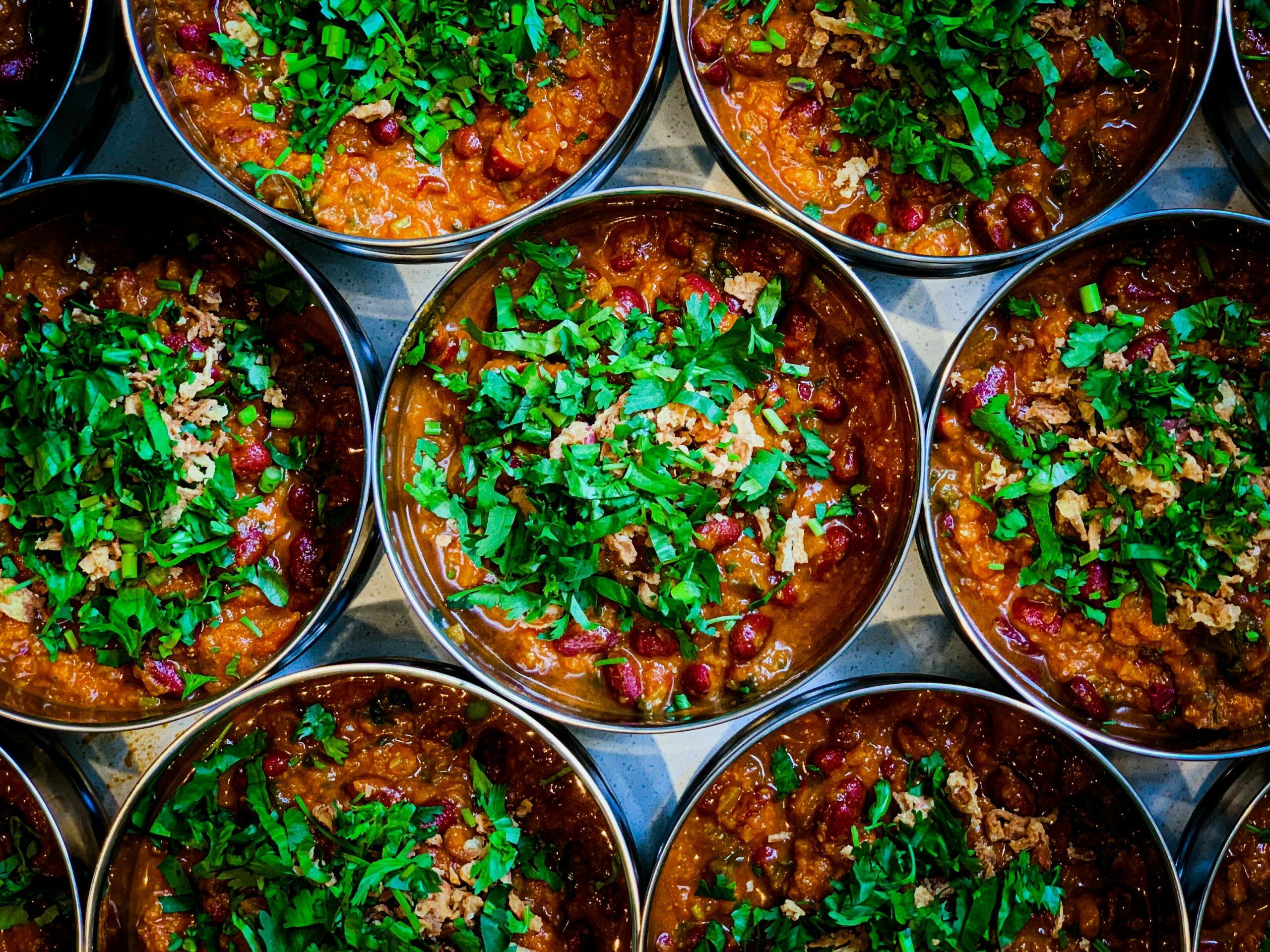 over head shot of the Majahma tiffins filled with delicious dishes with green plants on the top of it. Five reasons to try Majahma