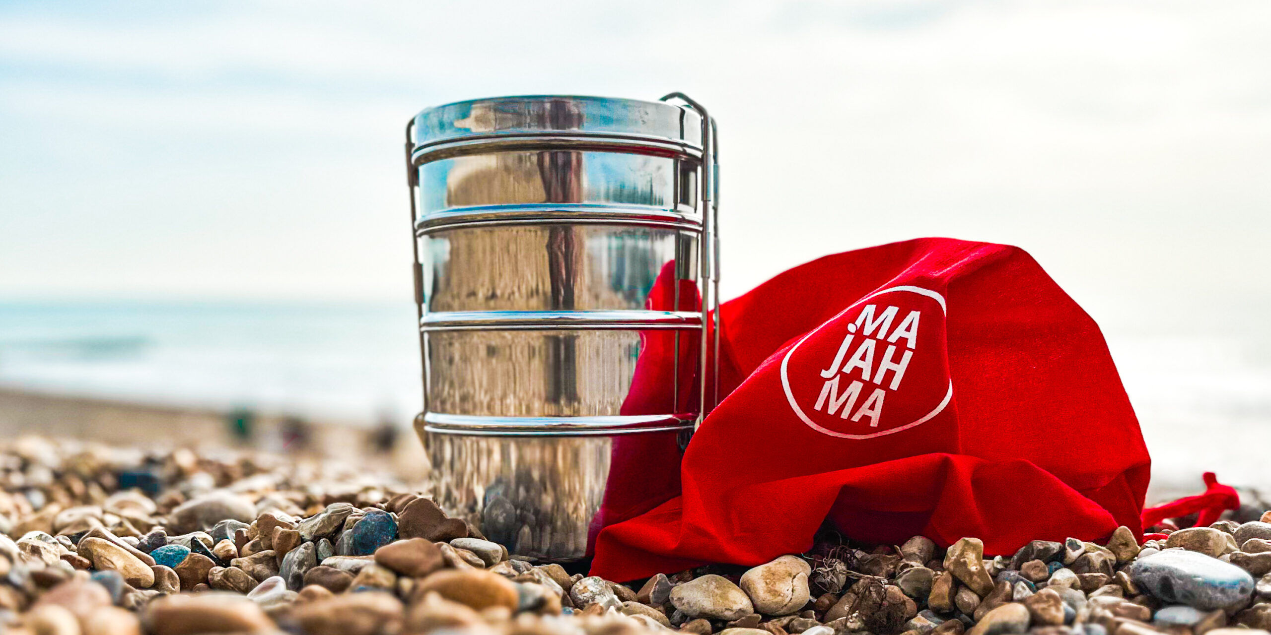 Majahma tiffin with red Majahma bag on Brighton beach