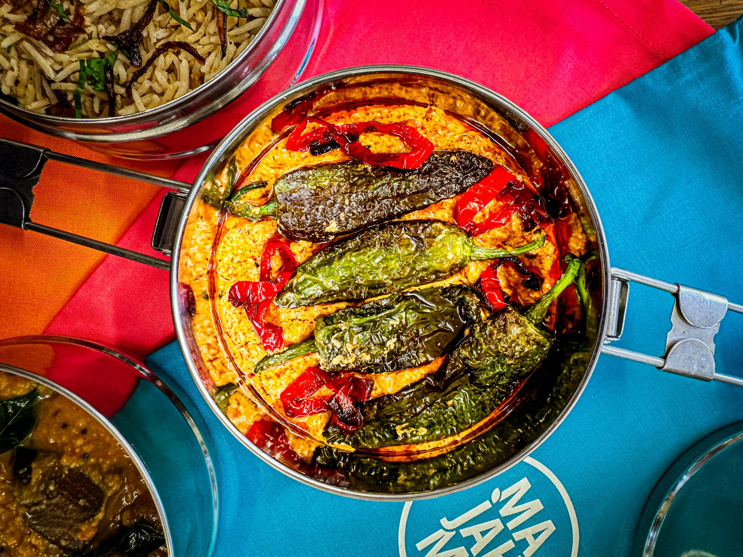 over head shot of Majahma tiffin with yellow dish with peppers on the top