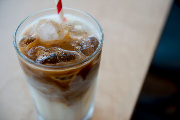 Overhead of an iced late in a glass, with a red and white paper straw
