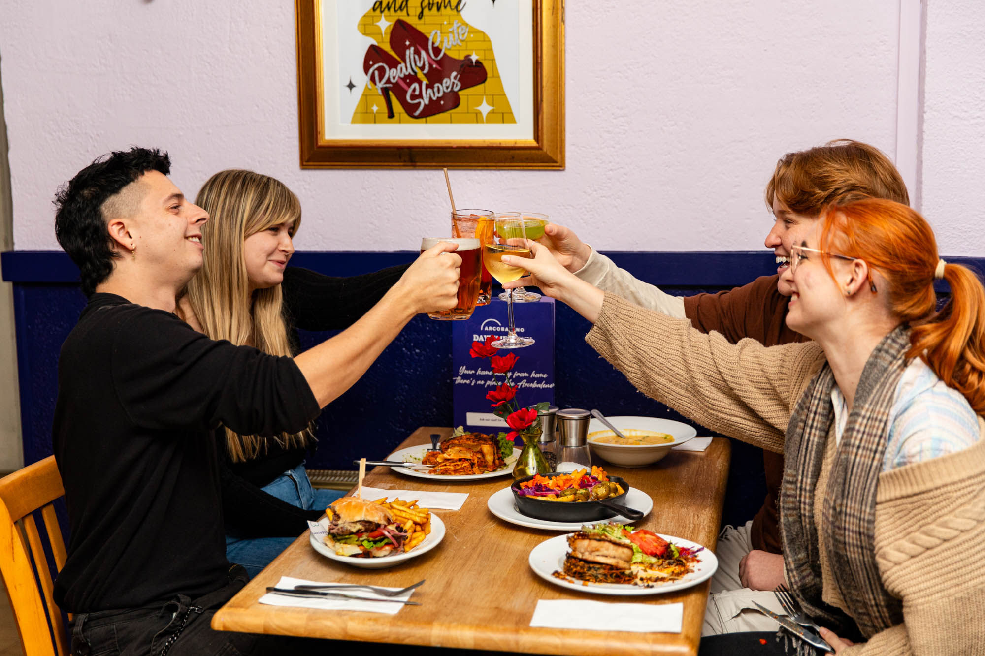 People cheersing their drinks at a table with food.