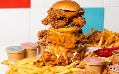 huge fried chicken burger with chips and sauces