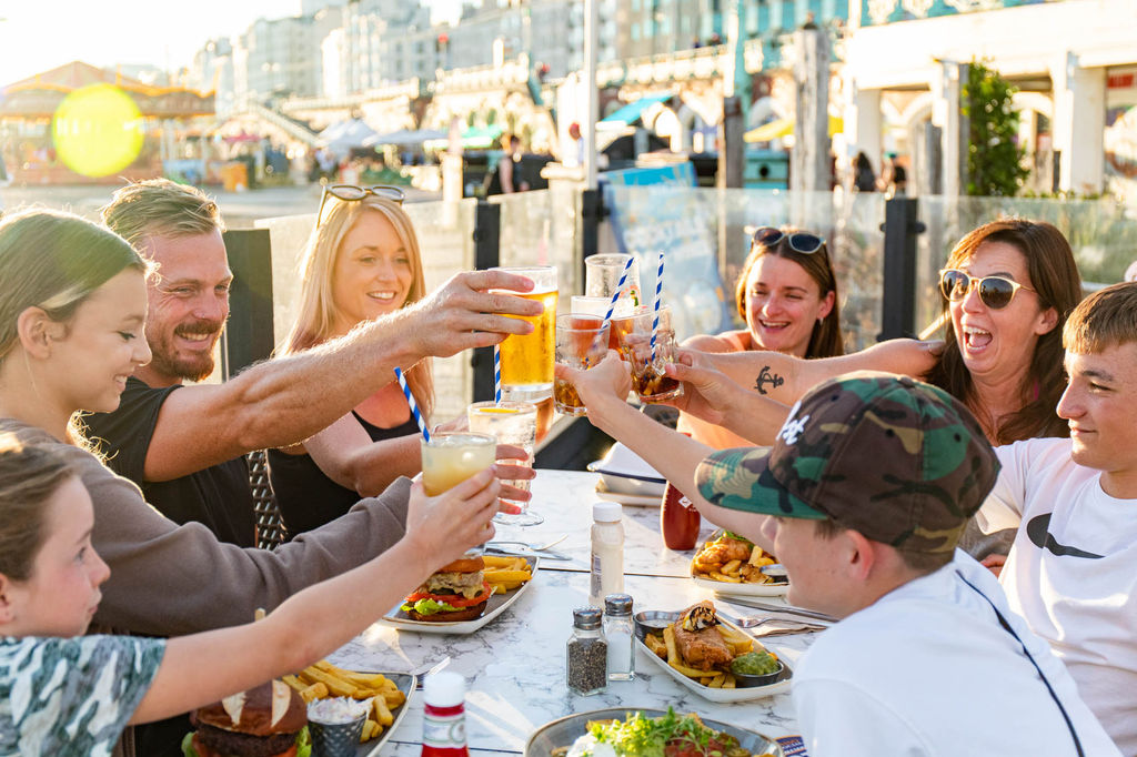 family by the table on the terrace having a toast, sunset in the background, Ohso is available for private dining Brighton or private hire