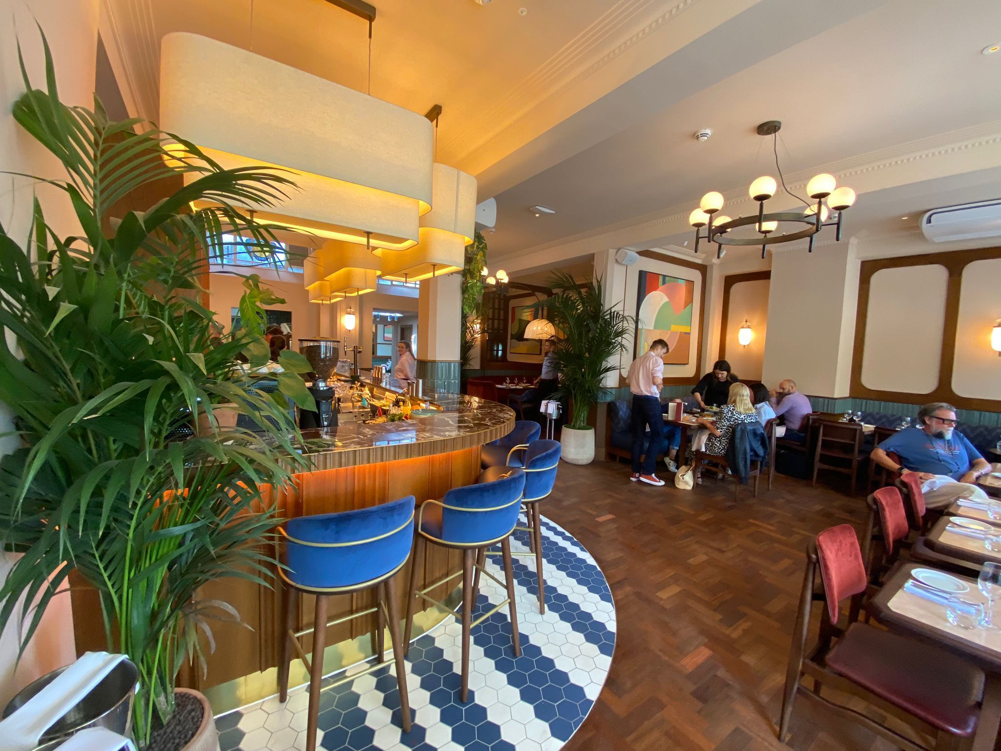 bar area of the Tutto, dim lights, wooden floor. blue and white carpet, blue bar stools