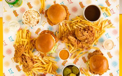 over head shot of the Lost Boys Land table with three chicken burgers, fries and sauces. Part of our Halal restaurants in Brighton guide