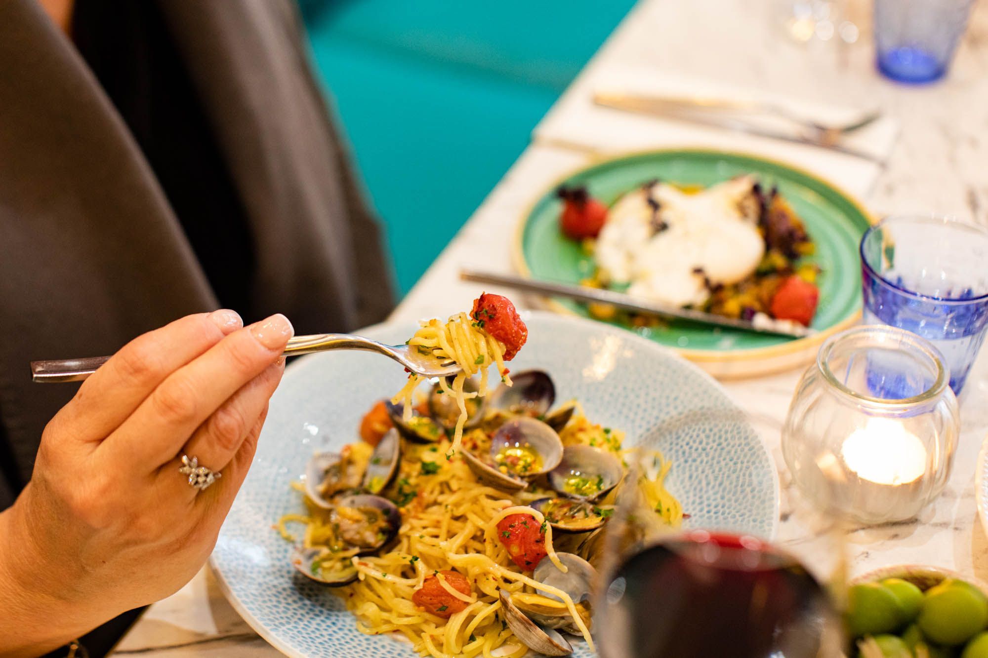 woman's hand holding fork above the pasta plate