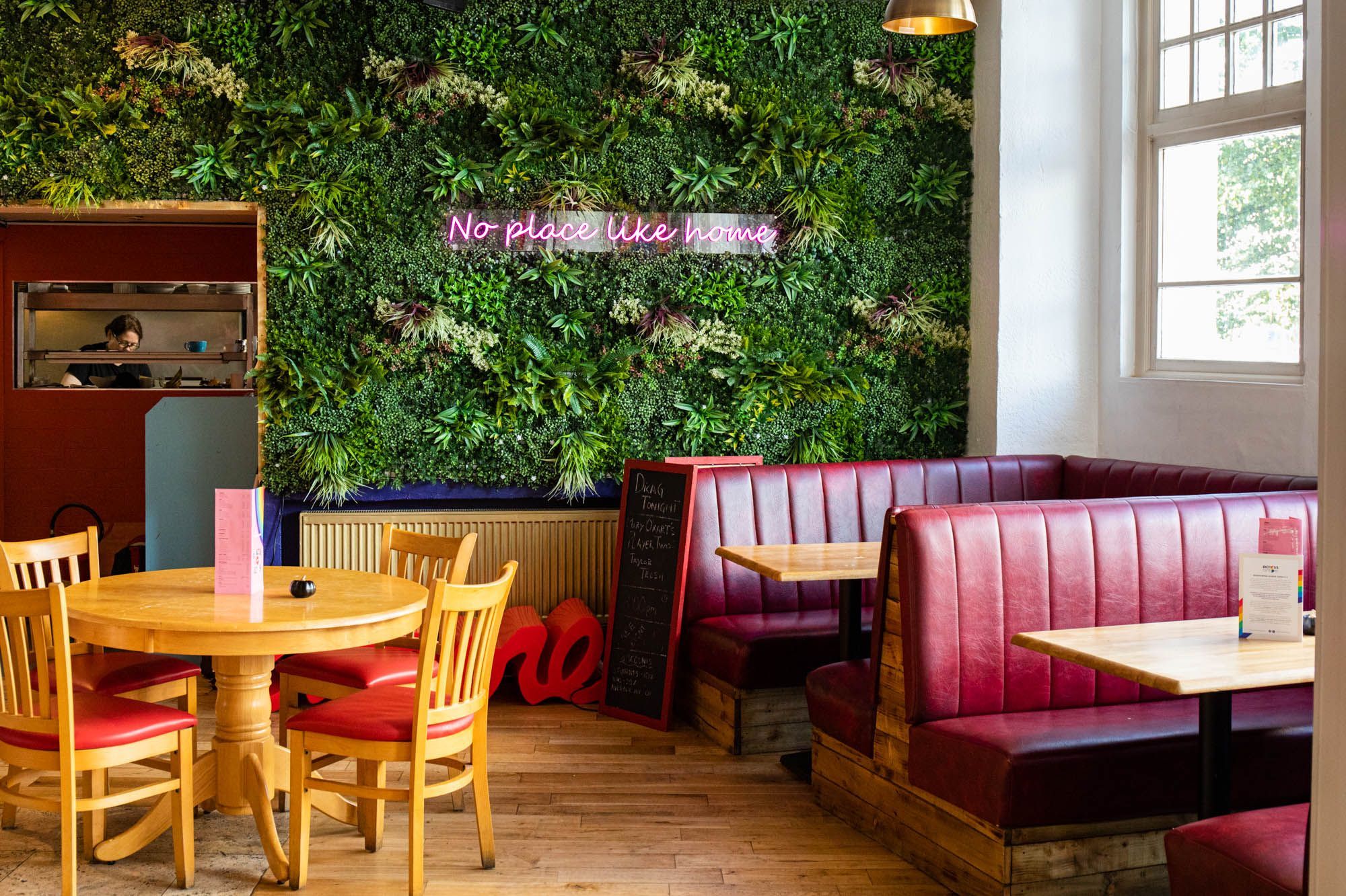 green corner of the bar with diner seating and plant wall