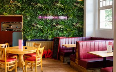 green corner of the bar with diner seating and plant wall