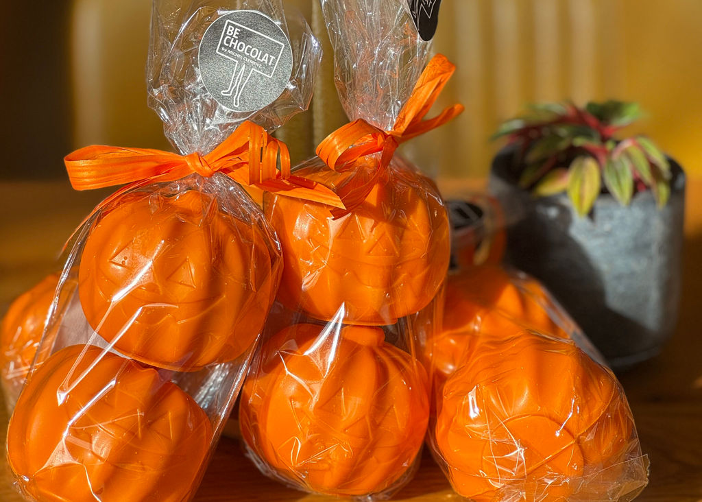 Halloween chocolates in the shape of pumpkins wrapped in plastic and stacked up.