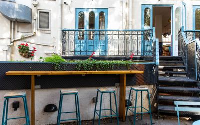 Arcobaleno garden with bar stools and wooden bar tables, baby blue doors and green plants