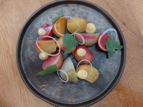 Overhead shot of a grey slate coloured plate with quarters of beetroot and drops of quince preserve