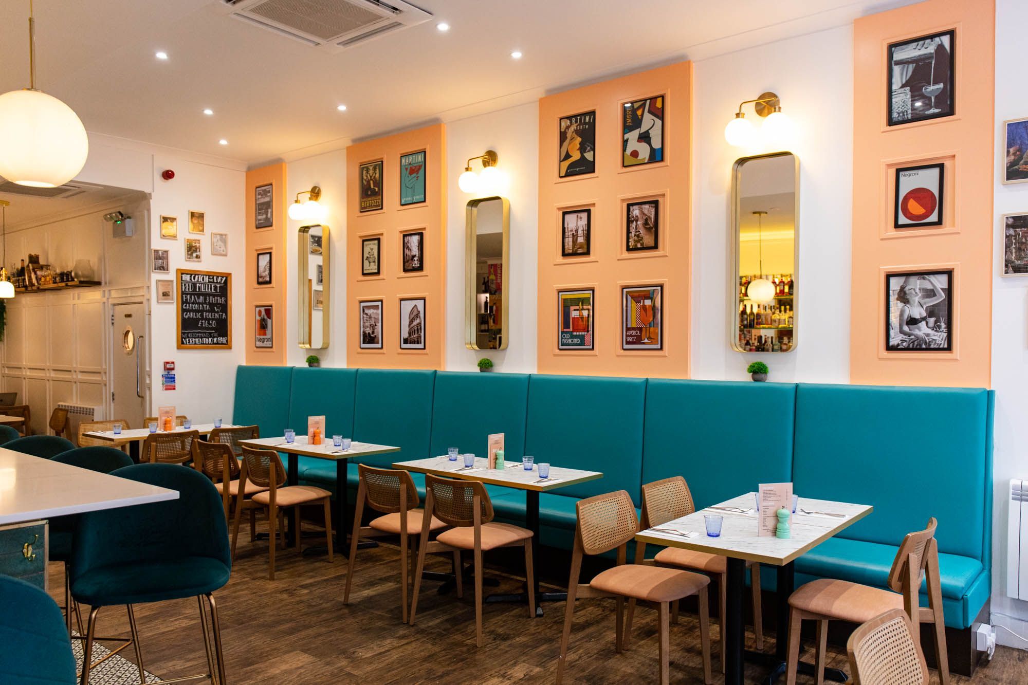interior of Pesca Trattoria, blue diner seating with white tables and brown chairs, peach coloured parts of the wall