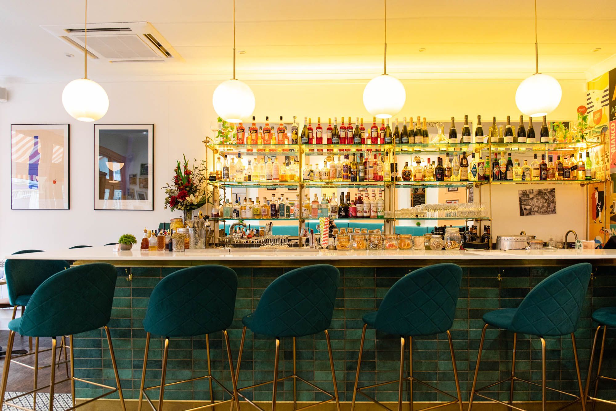 spacious bar area of the pesca trattoria Hove, dark green bar and bar chairs, big range of alcohol drinks