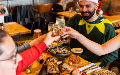 friends enjoying Christmas lunch at the Purezza vegan restaurant in Brighton. Purezza is one of our favourite Brighton restaurants in Kemptown. Pictured are friends dressed in festive outfits while enjoying pizza.
