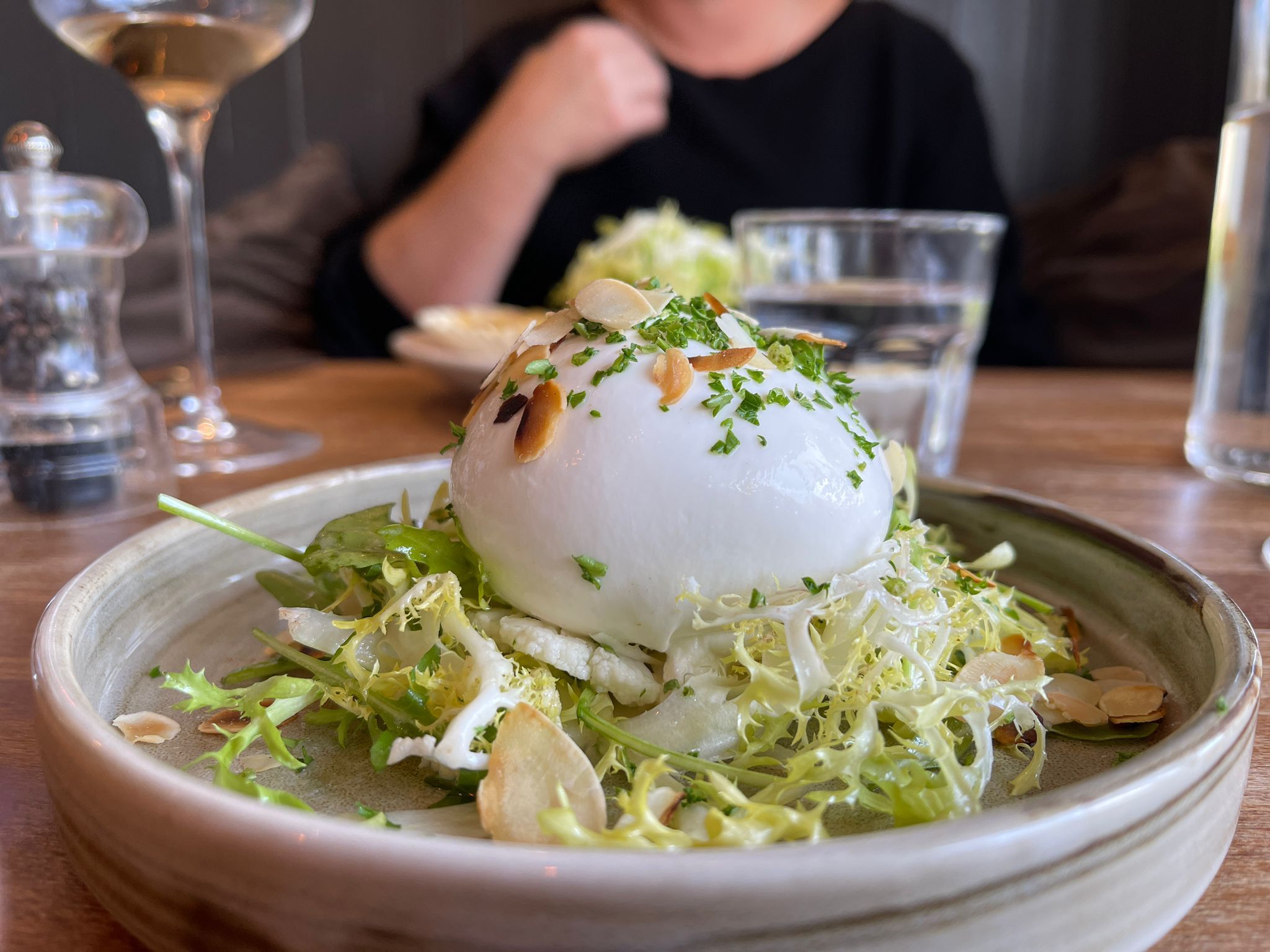 burrata, served on a bed of lightly dressed frisee and fennel, thinly sliced almond, and pickled cauliflower