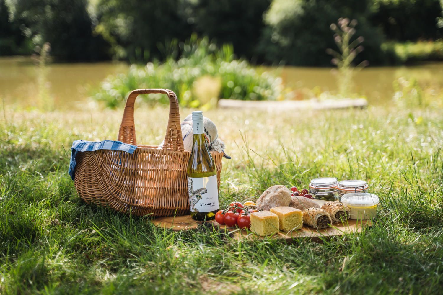 picnic basket and tray with snacks, fruits, vegetables. spread and bottle of white wine