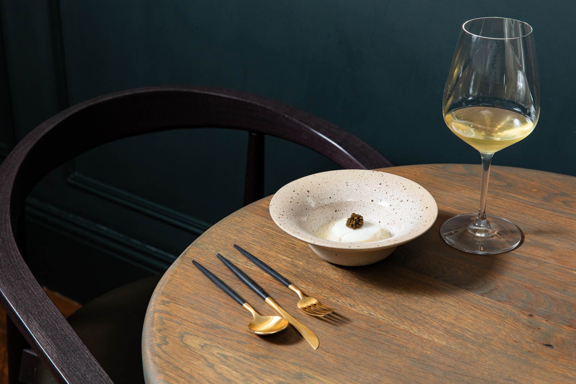 brown table, white plate with white dish, served with glass of white wine at Furna Brighton