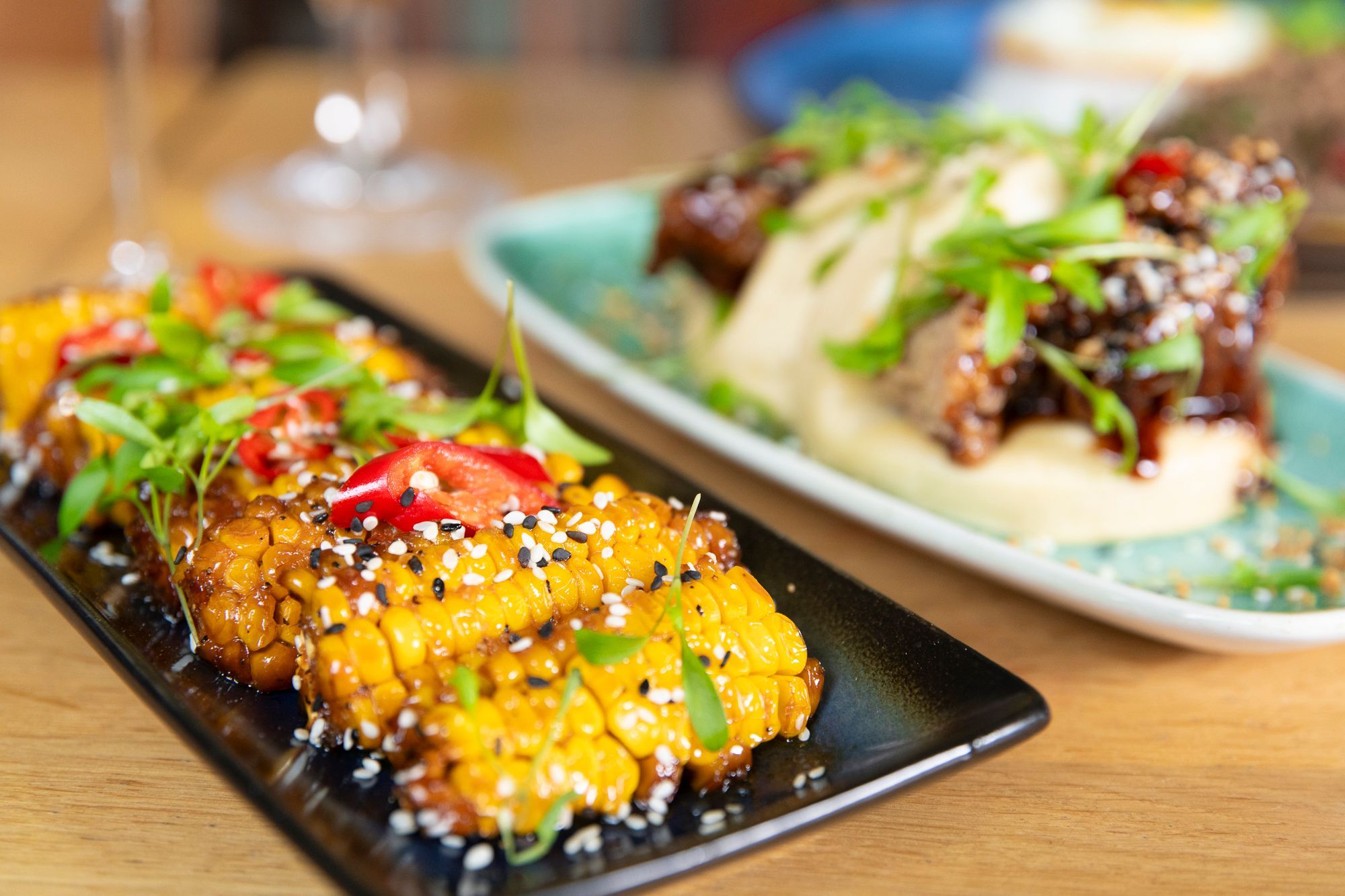 Close up shot of the cooked corns covered with sauce and paprika bits. bao buns visible in the background