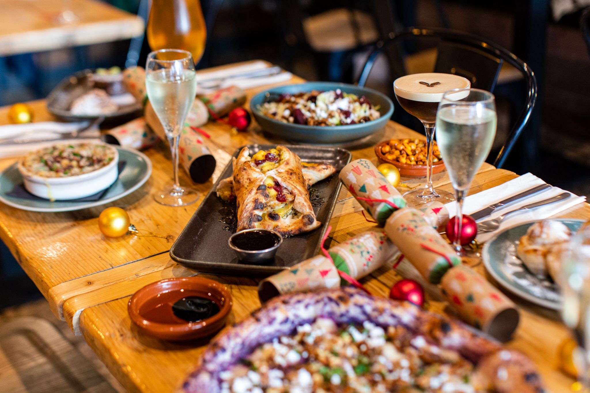 wooden table with festive decorations and delicious Italian food served with bubbles and espresso martini