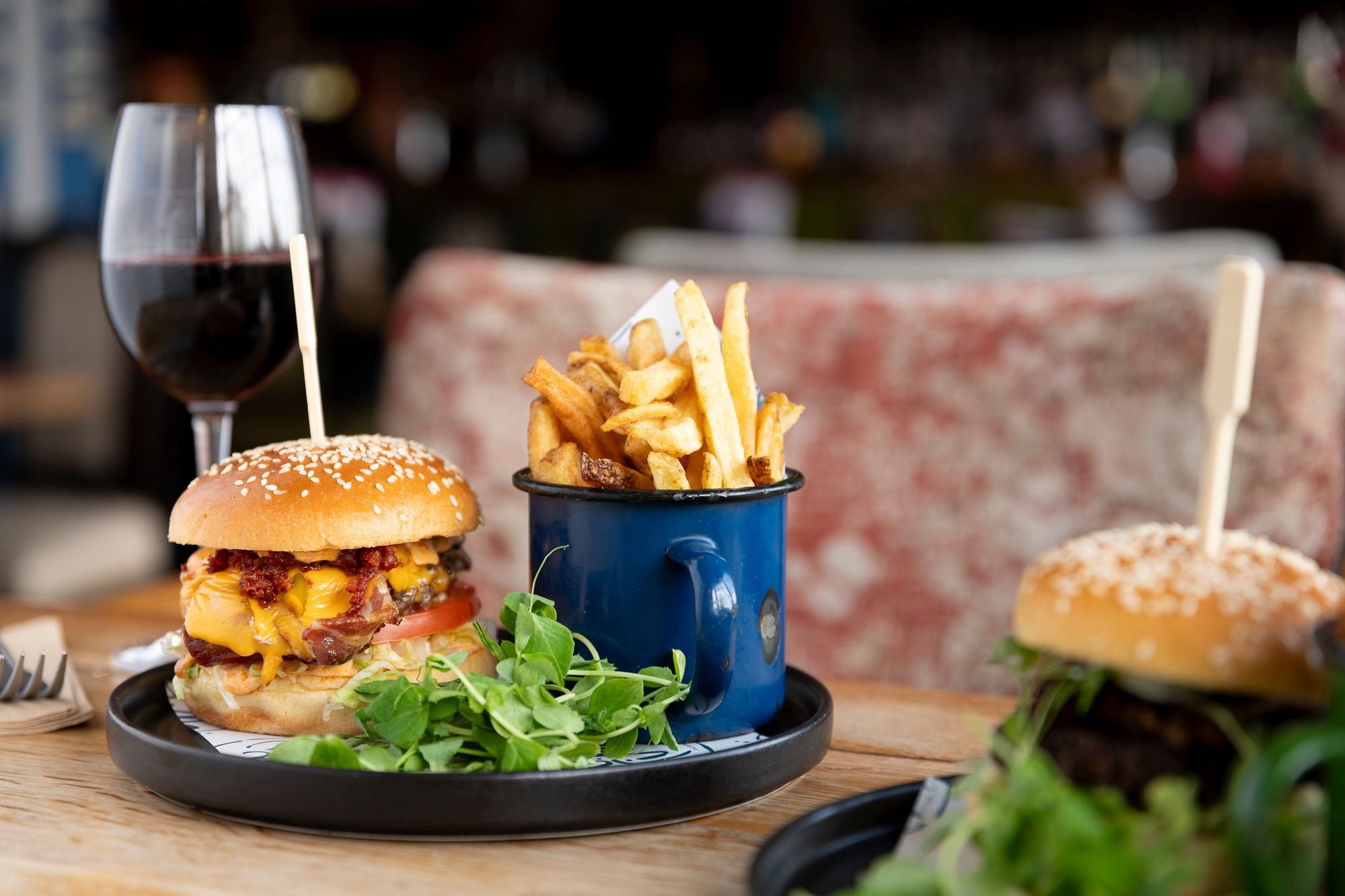 burger, salad and chips with red wine served at the table