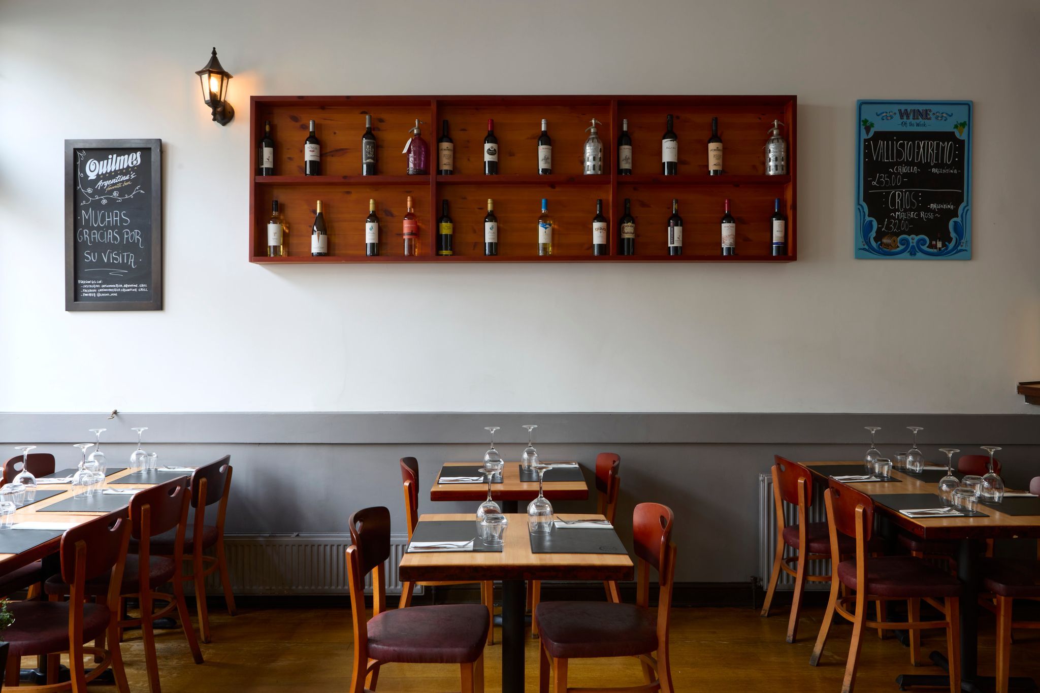 interior shot, wooden tables and chairs, and wine shelves on the wall 