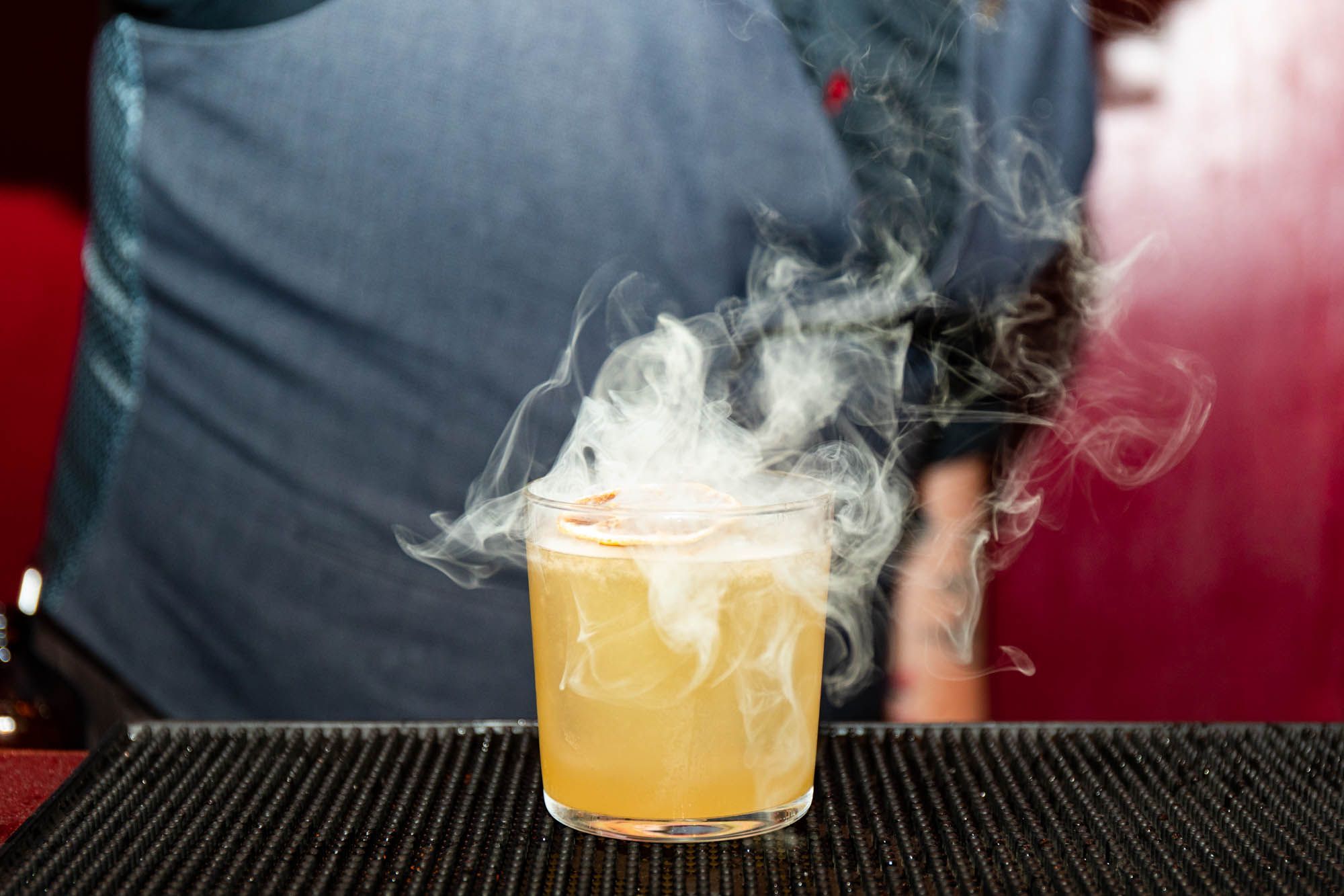 close up shot of the yellow cocktail and smoke coming out of it