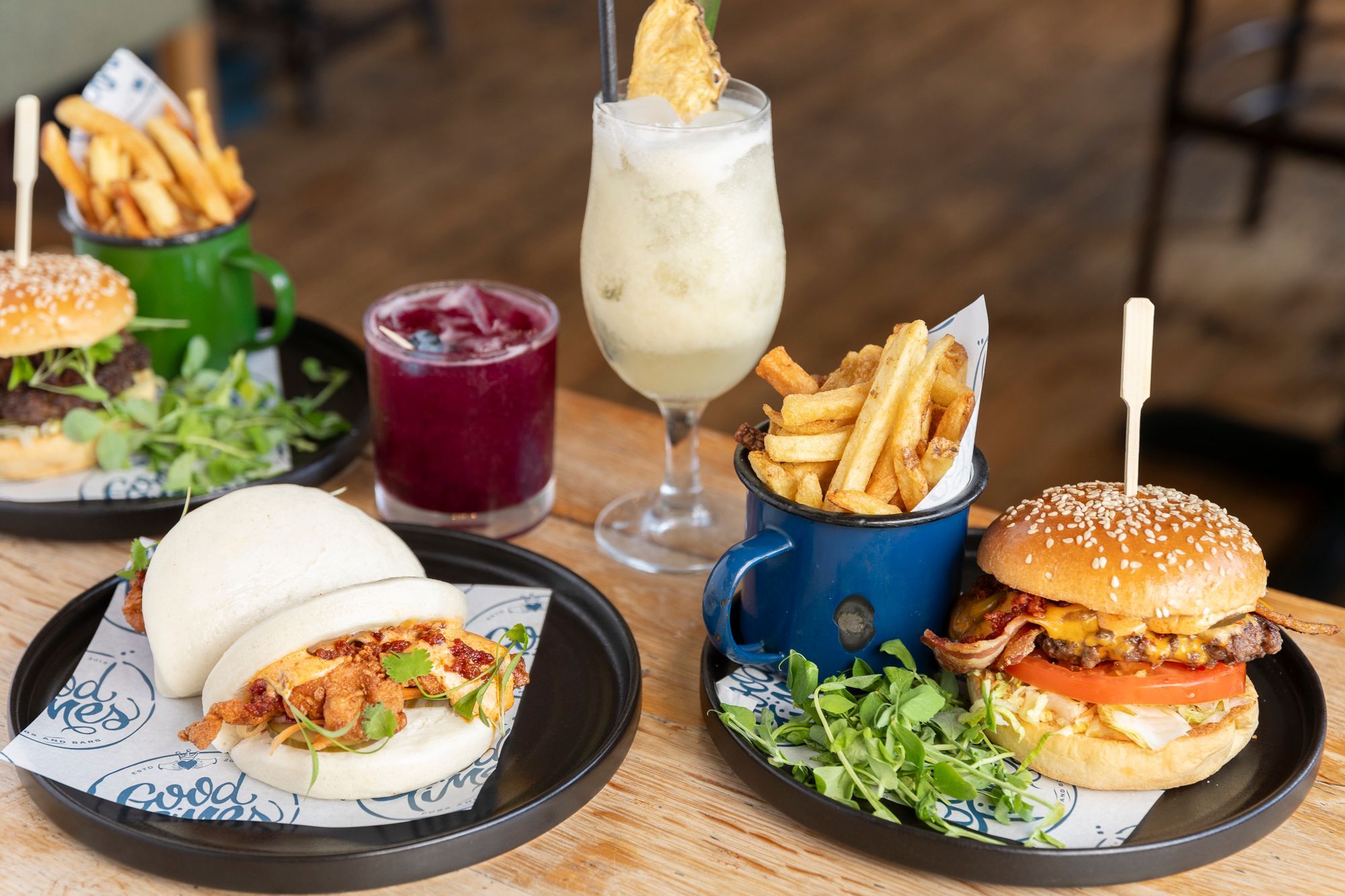 bao buns and burgers with chips served on the wooden brown table at this pub in Portslade, different cocktails included as well