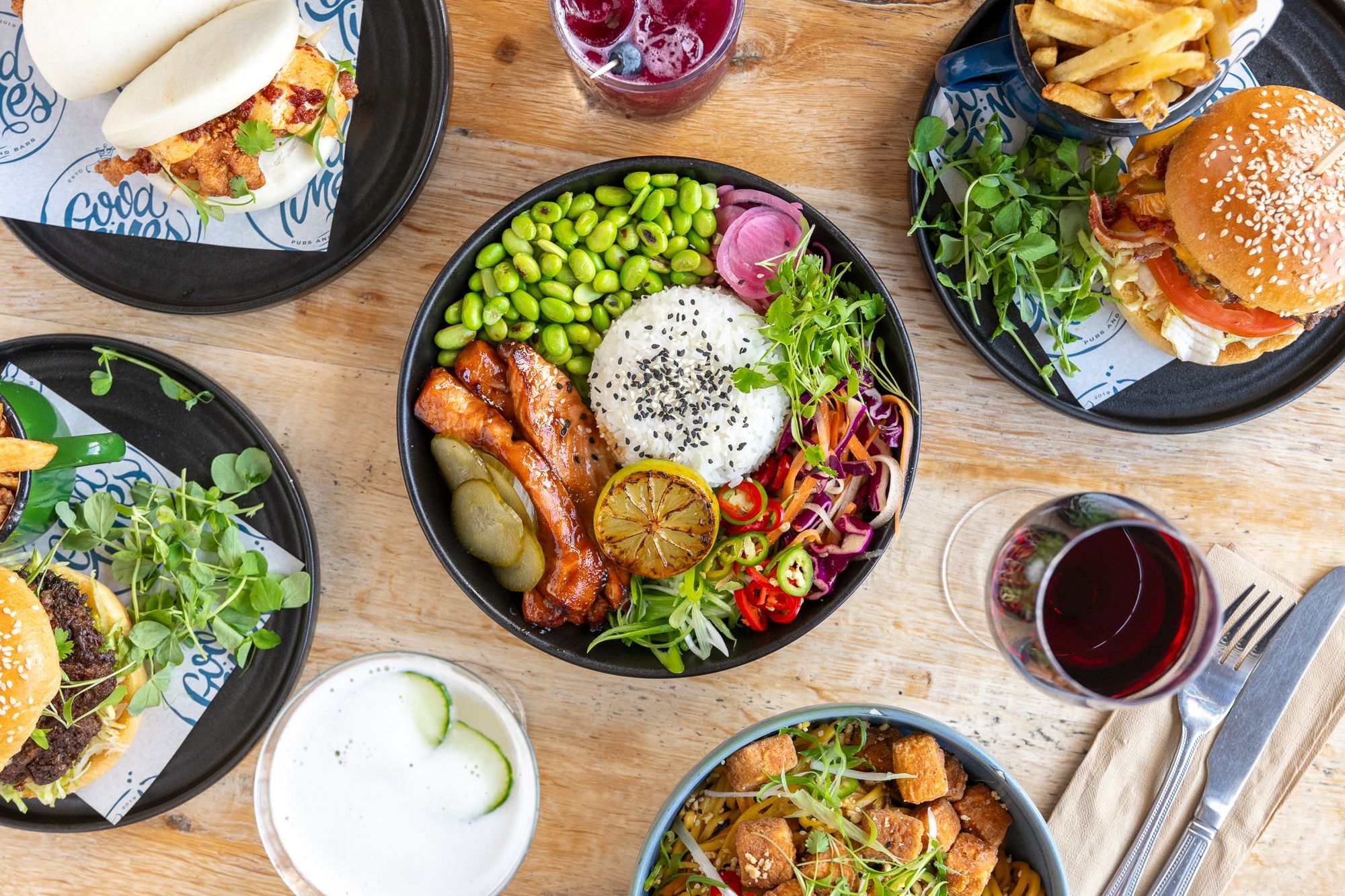 over head shot of the table laid out with five different dishes, including poke bowl. bao baos, burgers and drinks at the railway Inn