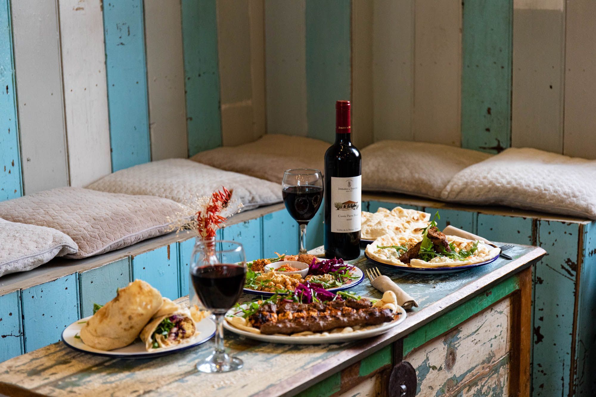 side shot of the Middle Eastern dishes served on the wooden table with two glasses of red wine