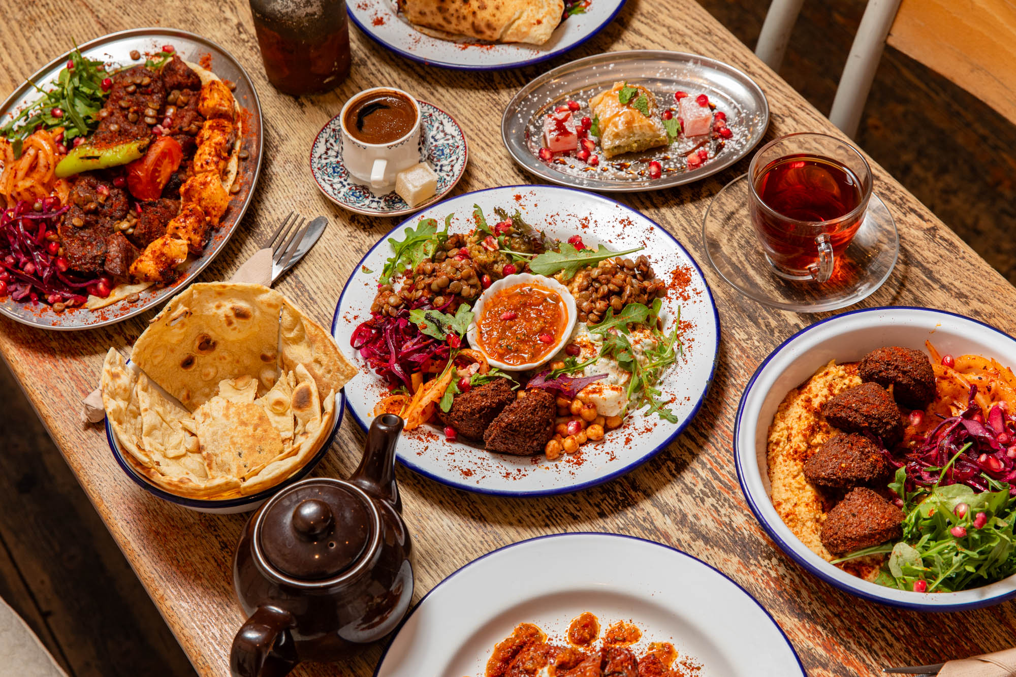 over head shot of the wooden table at lavash laid our with various middle eastern dishes 